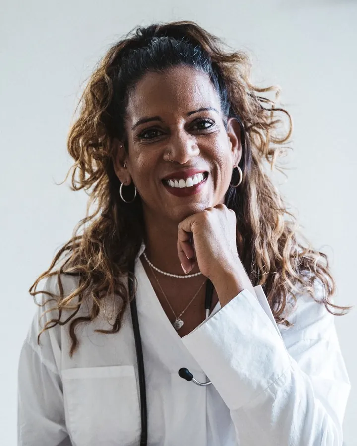 Dr. Camila Restrepo, smiling, chin resting on her hand, in a white coat