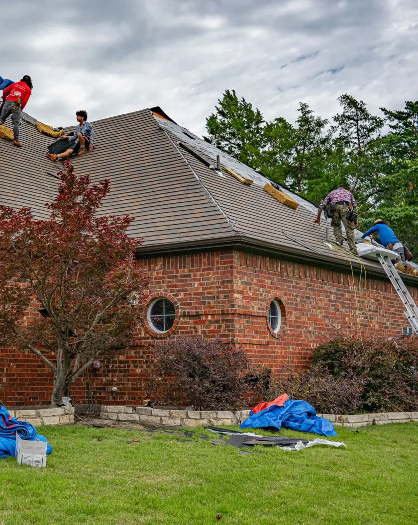 A Ridgewell crew re-roofing a red brick house, with ladders, tarps and new shingles going on