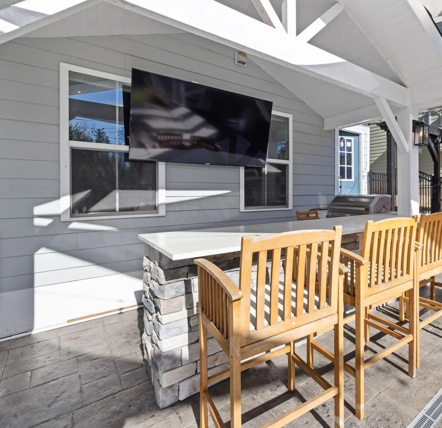 Covered back patio with a white beamed roof, an outdoor bar and wood stools