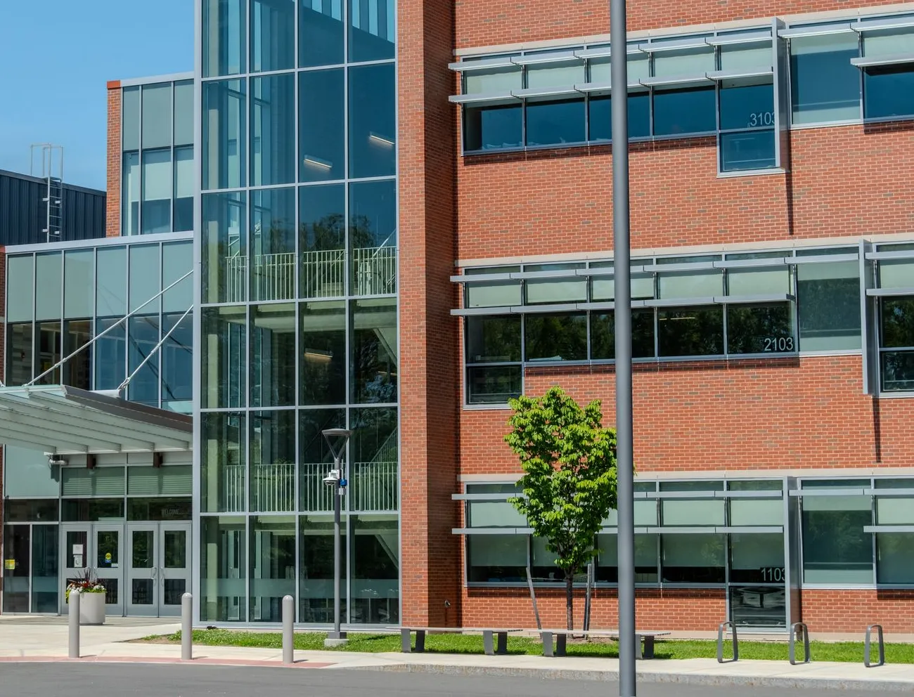 School addition with a glass stair tower, red brick classrooms and sunshades