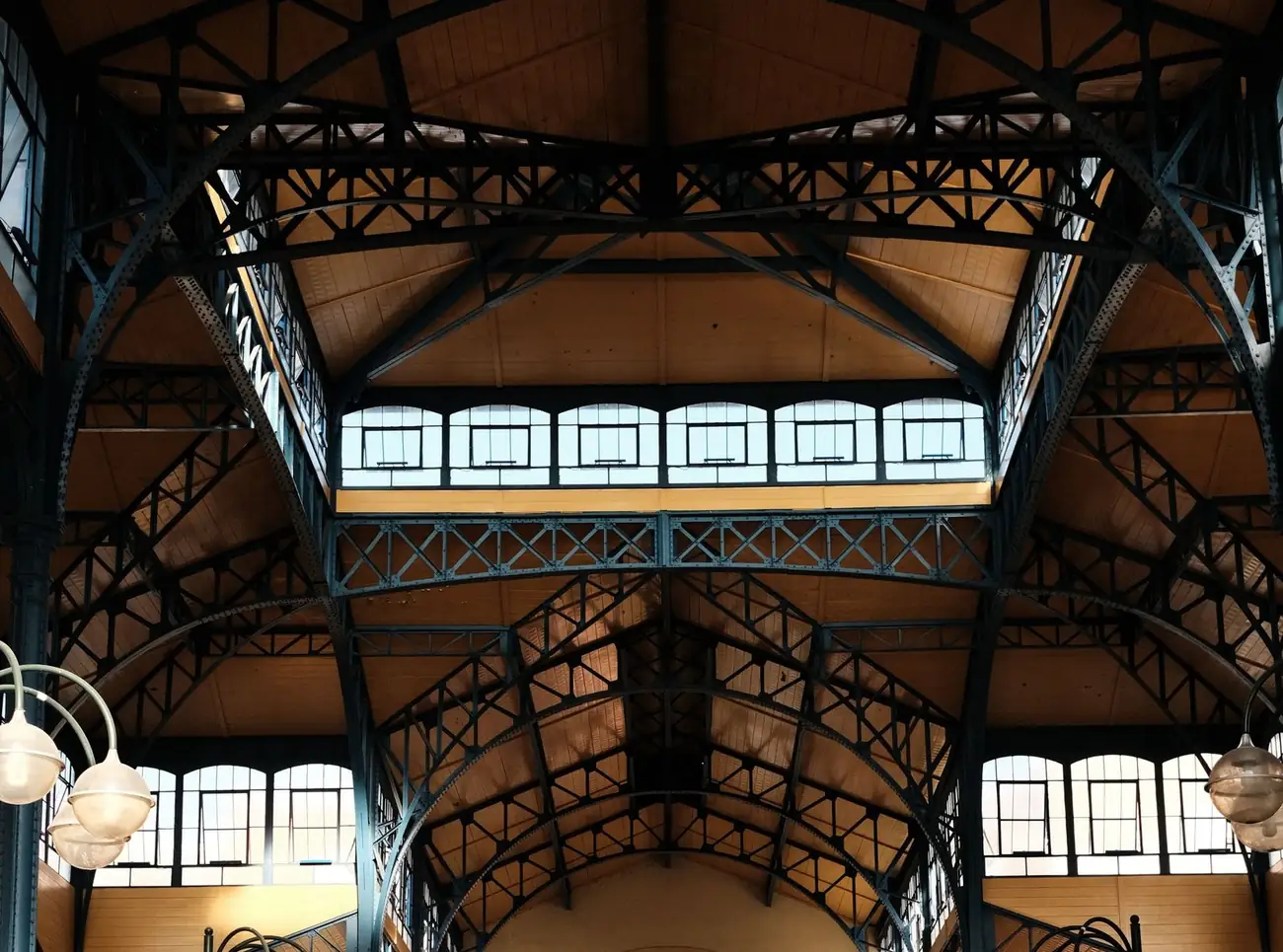 Restored iron roof trusses and clerestory windows inside a historic market hall